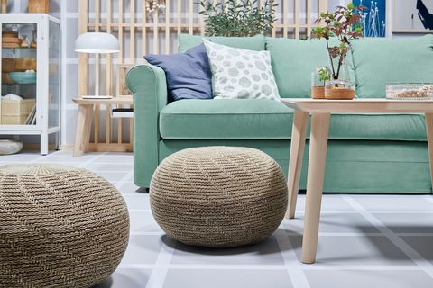 green sofa next to poufs of natural fibres