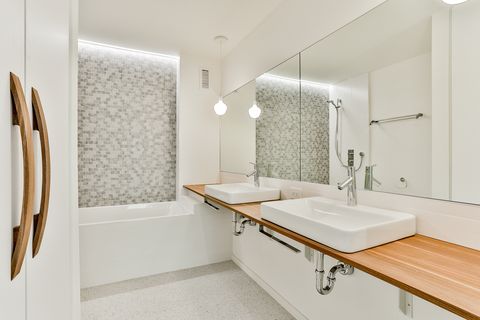bathroom decorated in white with a contemporary design with a bathtub and a floating wooden shelf