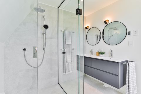 construction site shower with a modern design floating sink unit and two round mirrors
