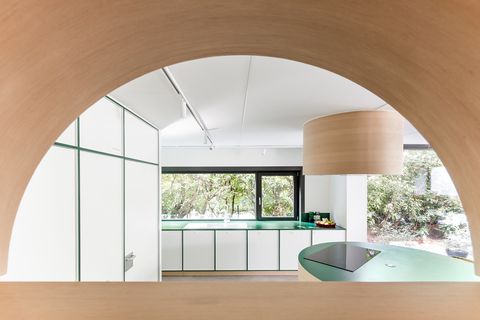 modern kitchen designed in white with green joints and a central wooden island that acts as a dining table
