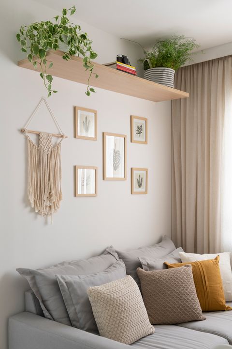 grey sofa with cushions and wall decorated with botanical illustrations and macramé