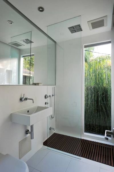 Bathroom with white walls and floor, with mirror that covers the entire wall