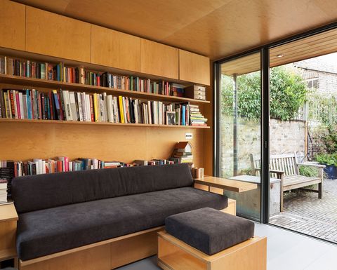 bookcase with books behind a sofa with matching footrests