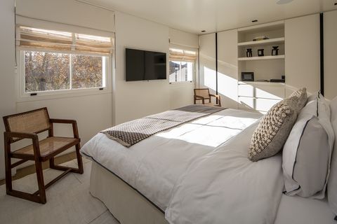 Minimalist style bedroom decorated in white with two wooden armchairs