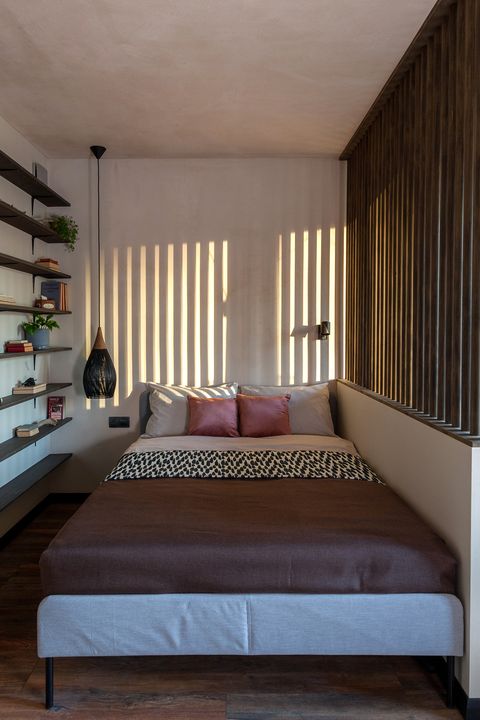 bedroom decorated in earth tones with wooden slats on the window