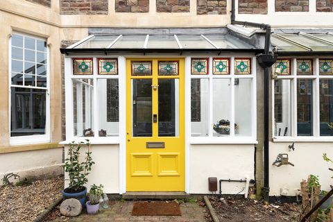 mudroom with yellow painted door and decorative stained glass